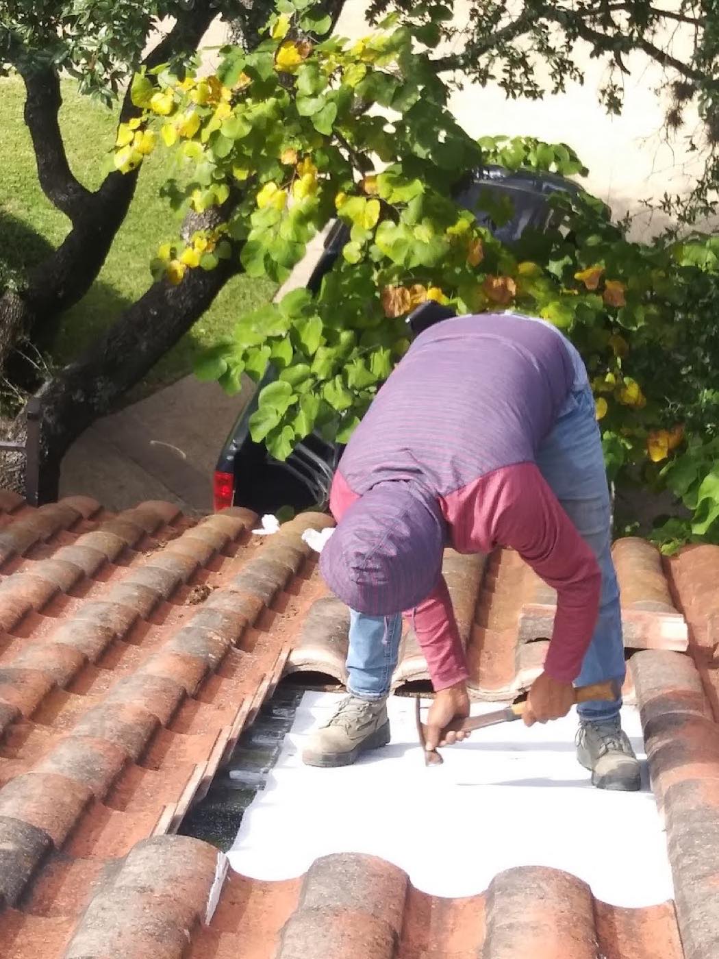 Hugo hammering down membrane on a Spanish tile roof